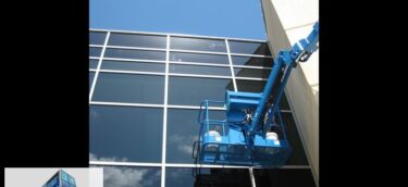 Glass scratch removal on tall hurricane glass curtain wall from JLG boom lift. Scratches visible towards top. Restoration project in Biloxi, MS